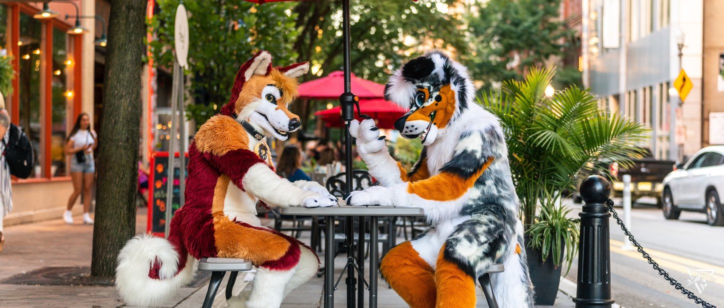 Two fursuiters sitting at a patio on Penn Avenue.