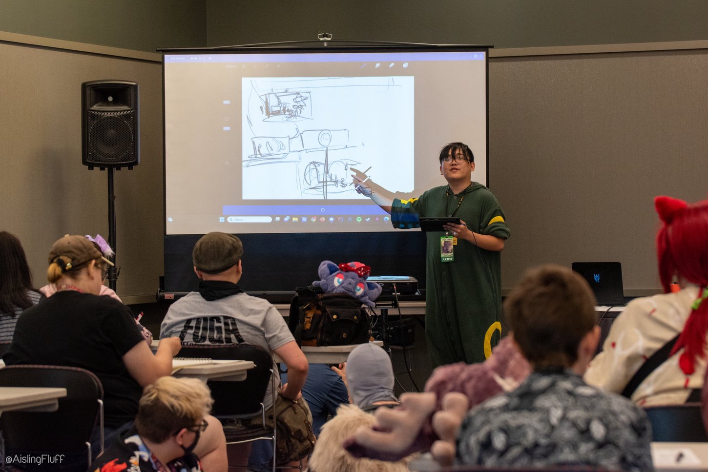 A panelist presenting their panel using a projector and digital drawings for Anthrocon 2023.