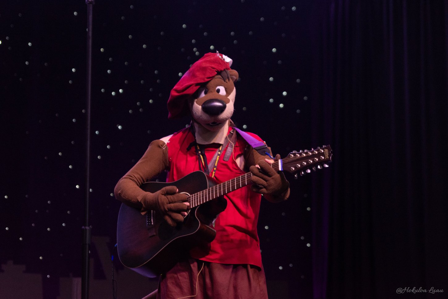 An otter performing the guitar on Anthrocon's performance stage.