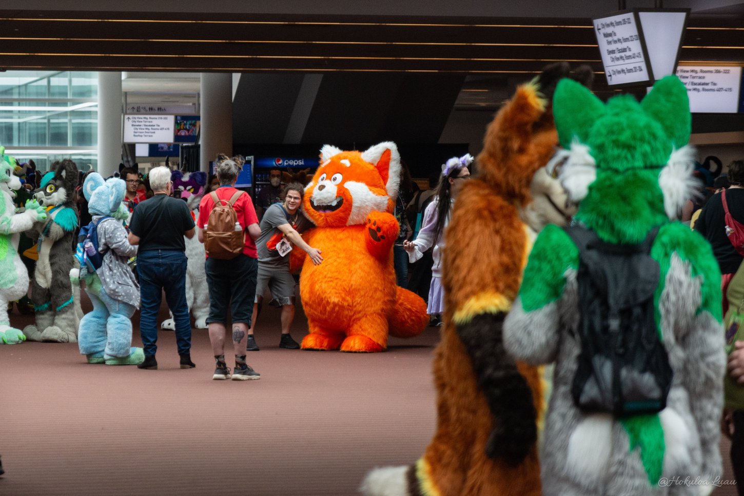 A photo of the foyer outside the Spirit of Pittsburgh Ballroom in the DLCC filled with many fursuiters and congoers.