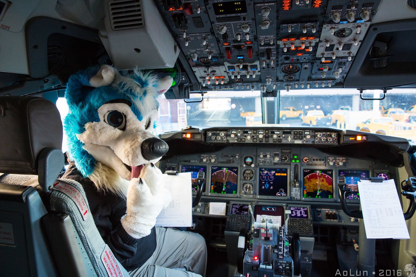 A fursuiter sitting in the cockpit of a commercial plane.